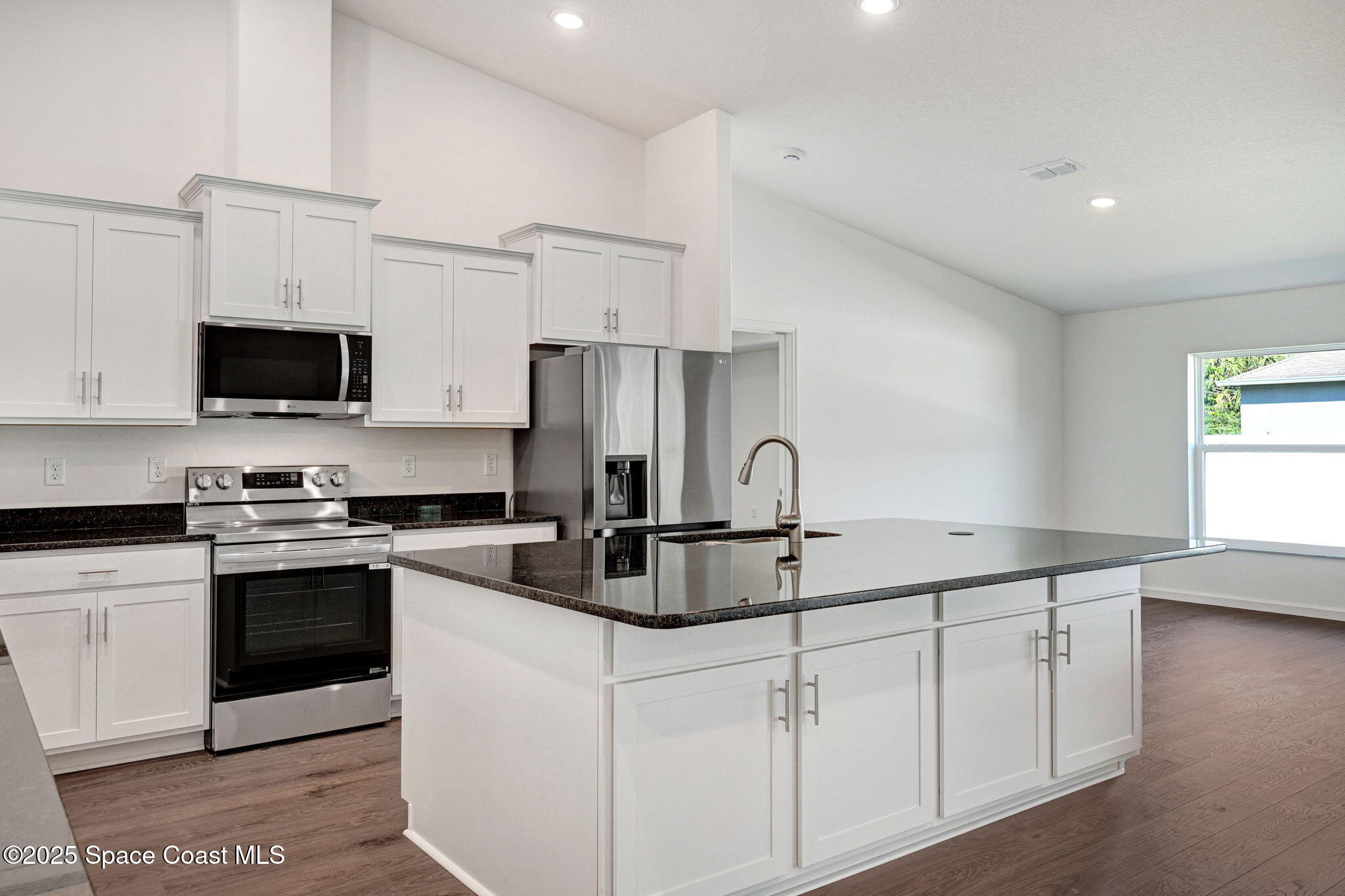 1089 Savery Road Palm Bay, FL 32908 - Photo 18 of 47 a kitchen with stainless steel appliances granite countertop a sink a stove a refrigerator a microwave and cabinets