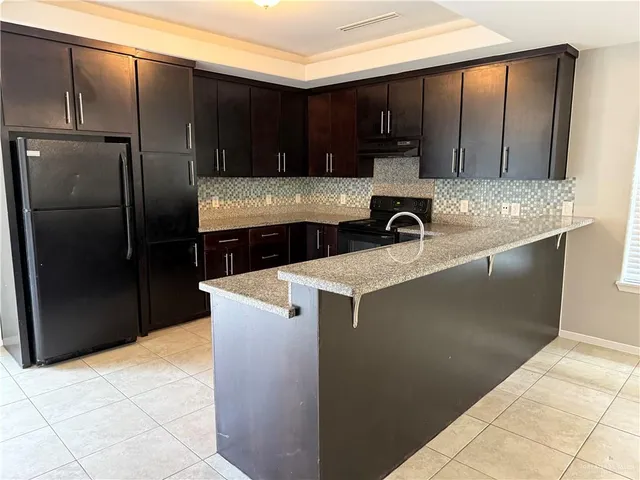 a kitchen with granite countertop a refrigerator and a sink