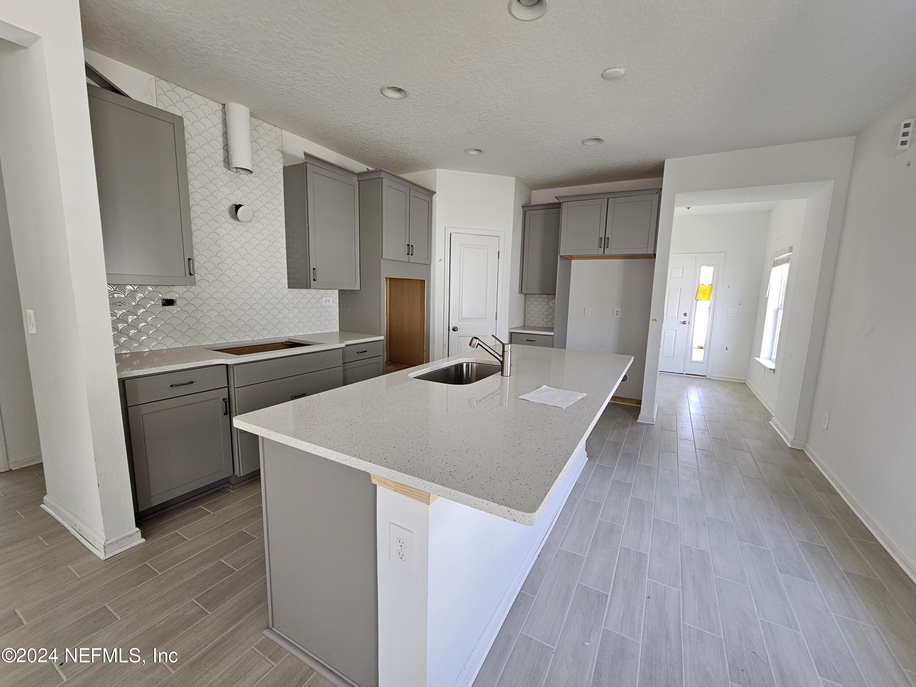 75232 Plumbago Trace Yulee, FL 32097 - Photo 5 of 79 a kitchen with stainless steel appliances a sink dishwasher a refrigerator a stove and white cabinets with wooden floor