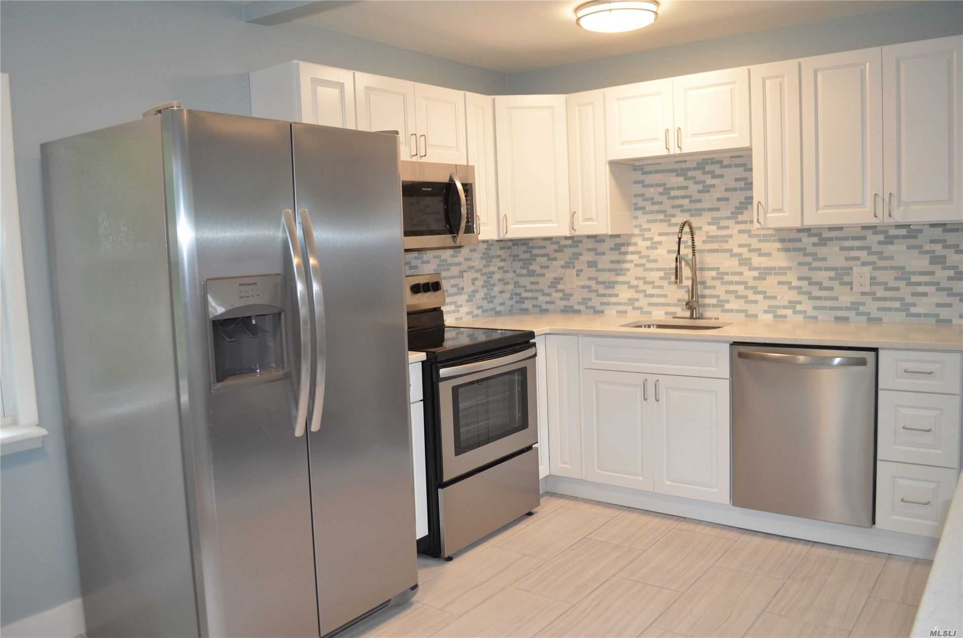 a kitchen with stainless steel appliances kitchen island granite countertop a refrigerator sink and cabinets