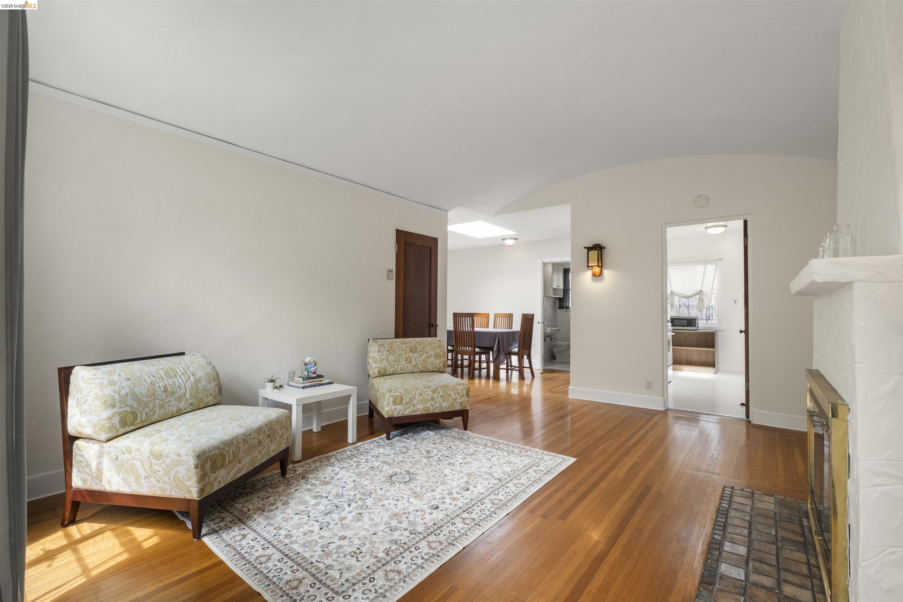 2444 Virginia Street, Unit B Berkeley, CA 94709 - Photo 16 of 39 Living space featuring wood-finish flooring, a fireplace with a brick hearth, and a curved ceiling detail