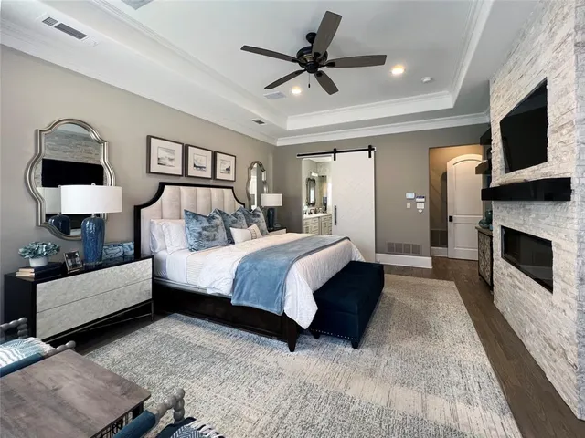 a spacious bedroom with a large bed a flat tv screen and a dresser