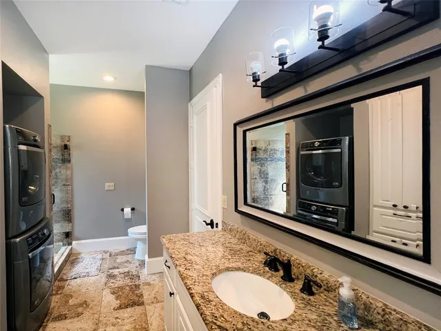 a bathroom with a granite countertop sink a mirror and shower