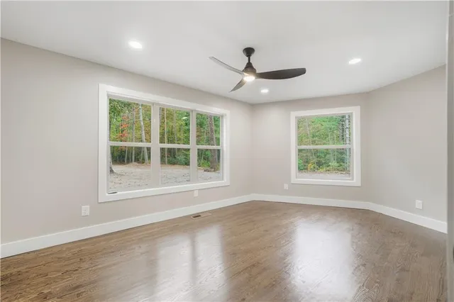 an empty room with wooden floor cabinet and windows