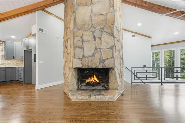 a view of an empty room with wooden floor fireplace and a window