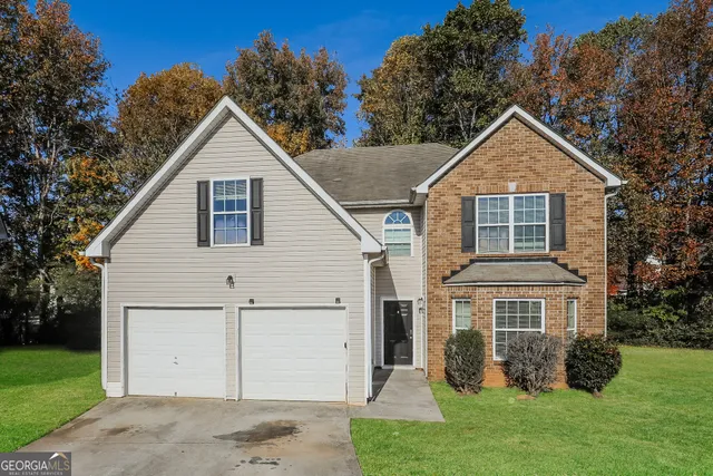 a view of a yard in front of a house with plants and large tree