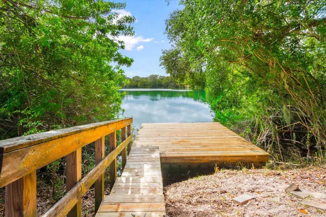 a kitchen with stainless steel appliances granite countertop wooden cabinets a sink dishwasher a stove and a refrigerator with wooden floor