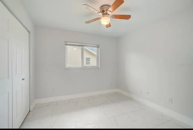 an empty room with windows and fan