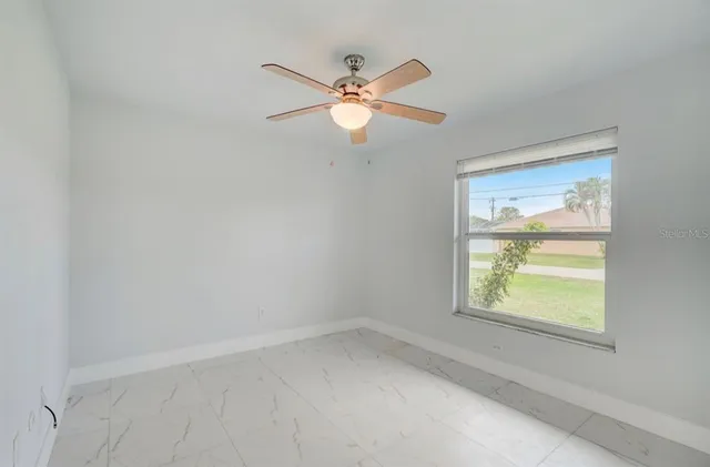 an empty room with a window and a fan