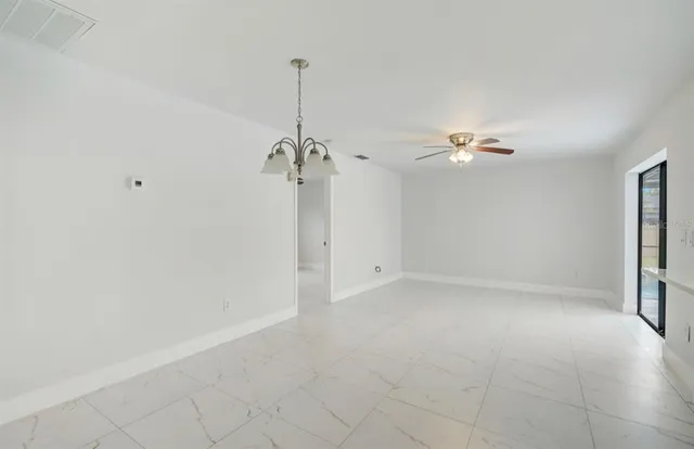 a view of a room with a chandelier fan and windows