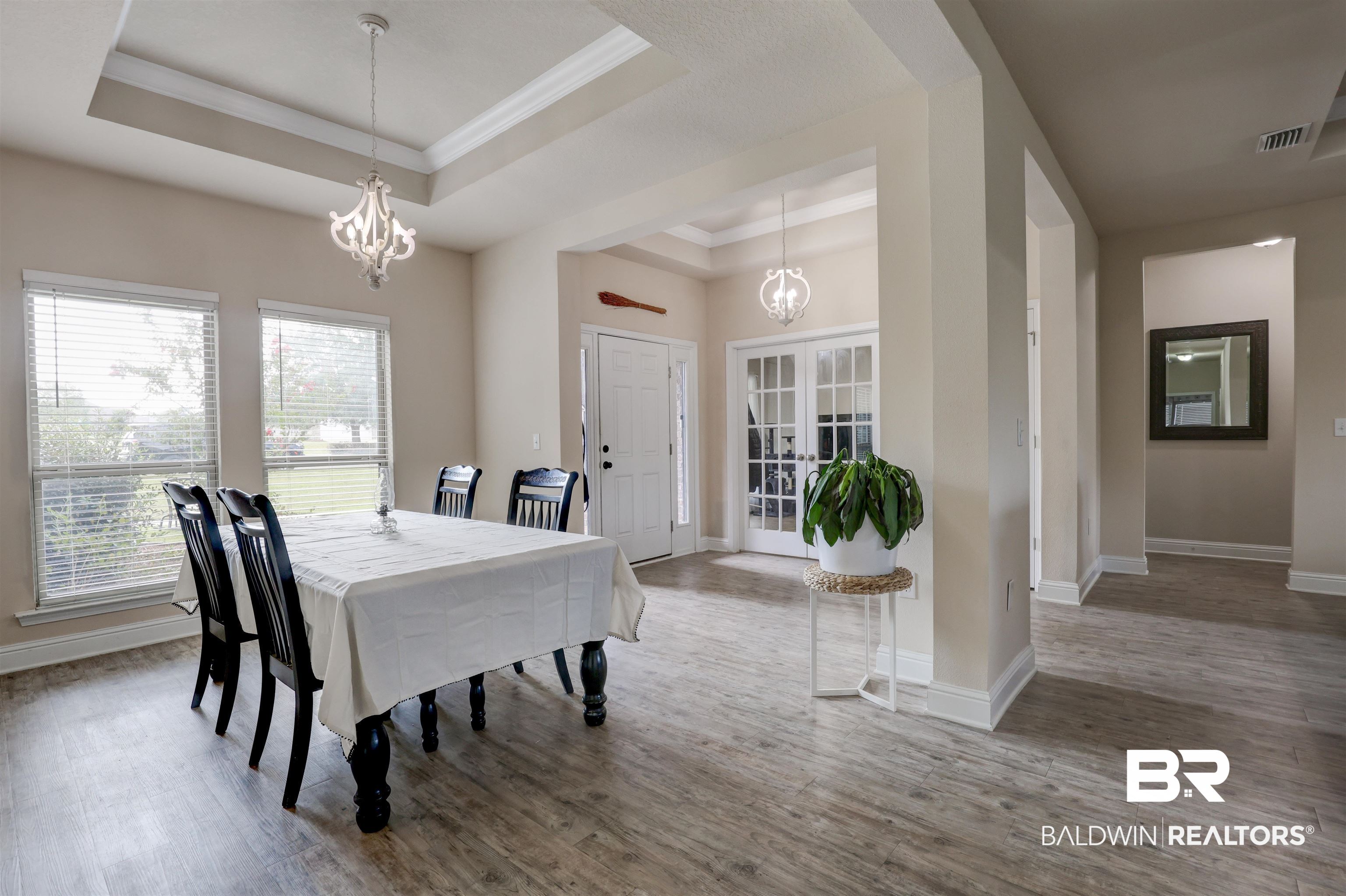 21902 Yosemite Boulevard Fairhope, AL 36532 - Photo 3 of 32 Dining area with a notable chandelier, crown molding, hardwood / wood-style flooring, and a tray ceiling