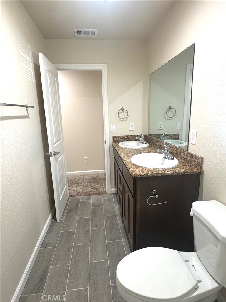 1339 Playa Del Rey Drive Merced, CA 95348 - Photo 39 of 48 a bathroom with a granite countertop sink toilet a mirror and vanity