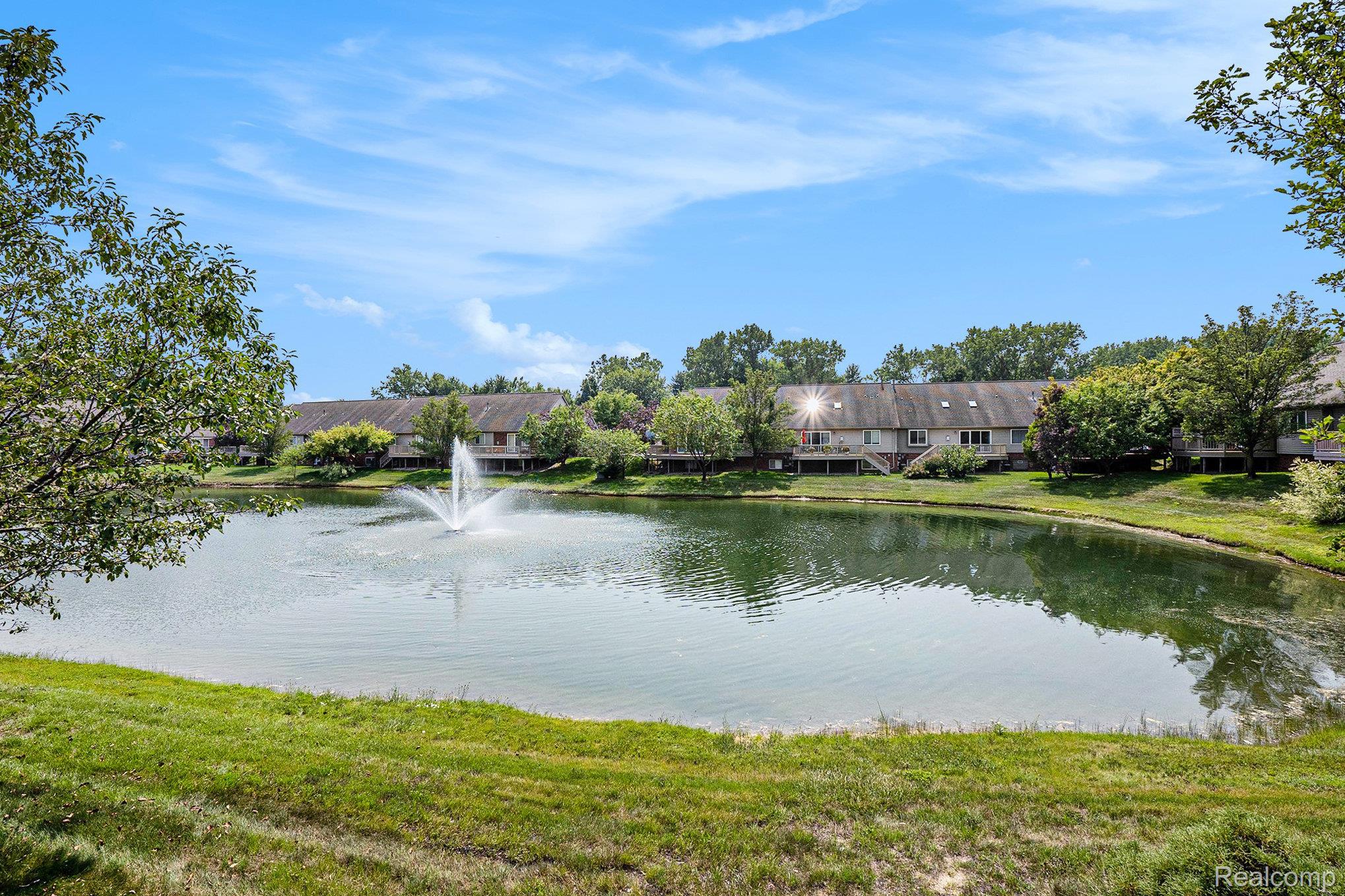 5477 Victory Circle Sterling Heights, MI 48310 - Photo 28 of 32 Pond with a central fountain feature, surrounded by green grass and mature trees