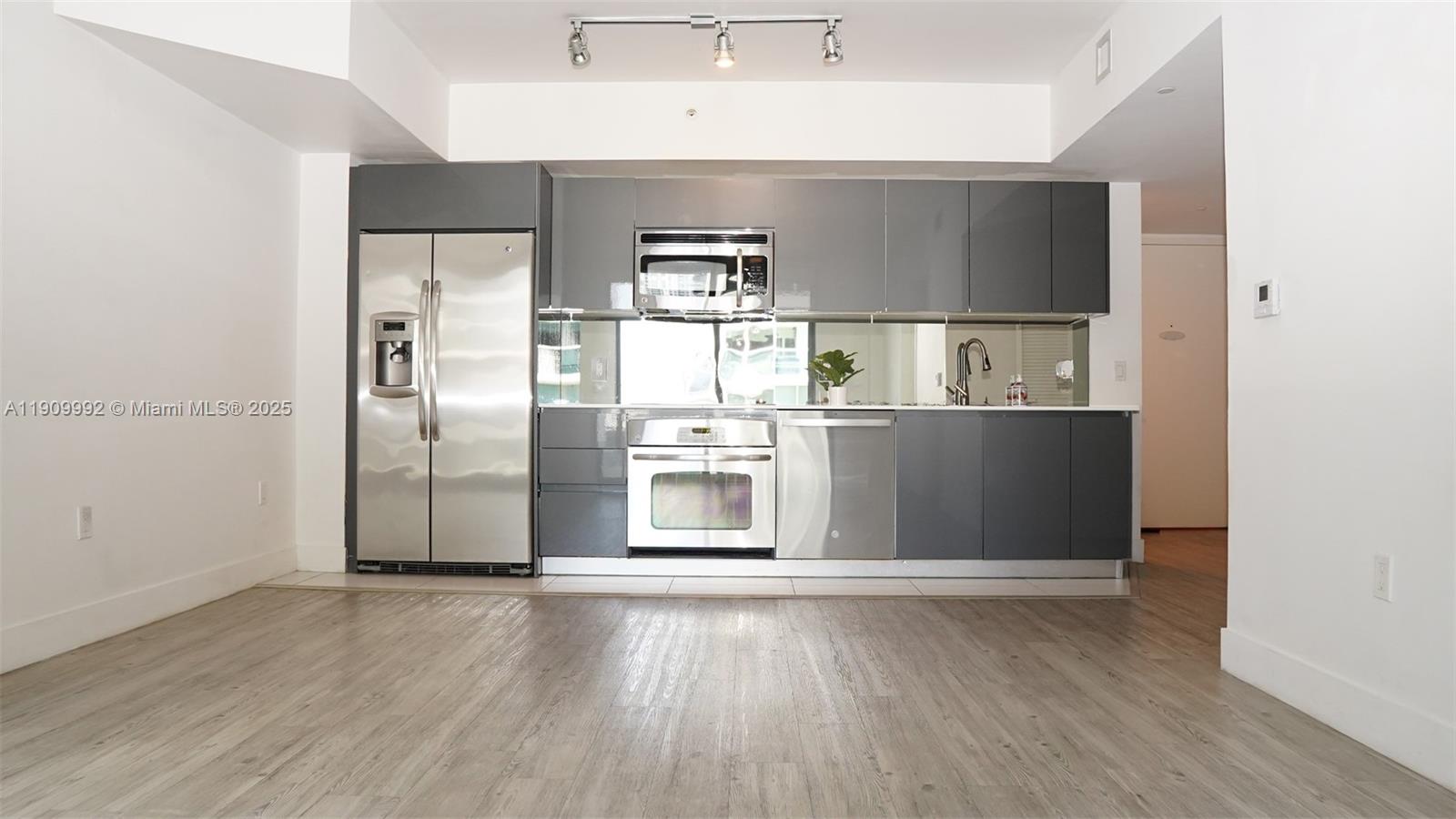 31 Southeast 6th Street, Unit 1108 Miami, FL 33131 - Photo 4 of 22 a kitchen with granite countertop a refrigerator and wooden floor