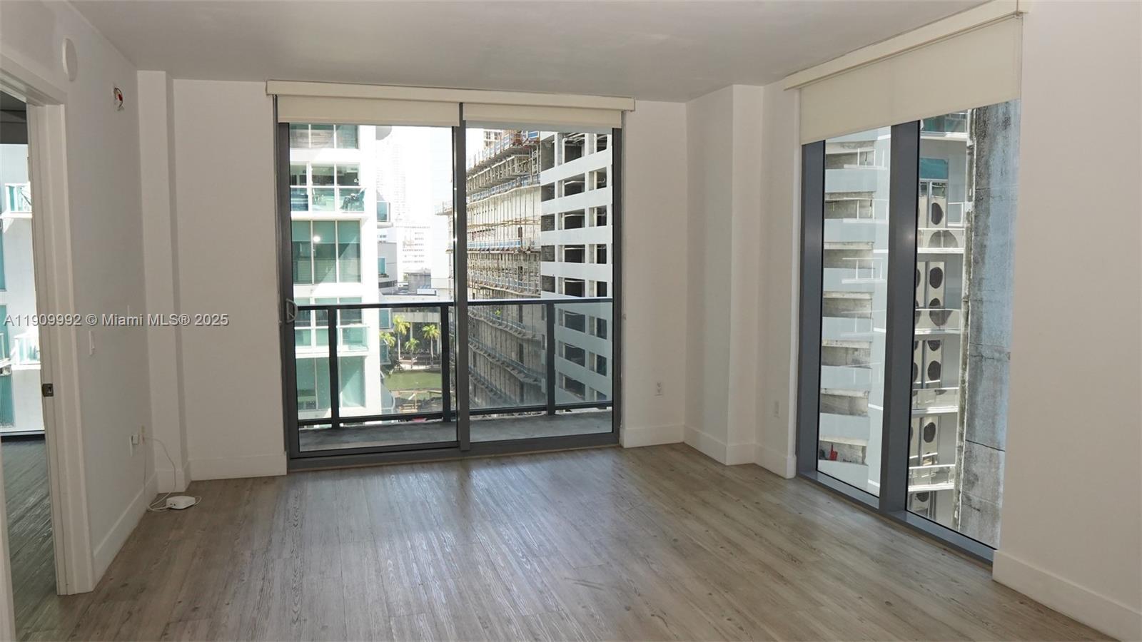 31 Southeast 6th Street, Unit 1108 Miami, FL 33131 - Photo 6 of 22 an empty room with wooden floor and windows