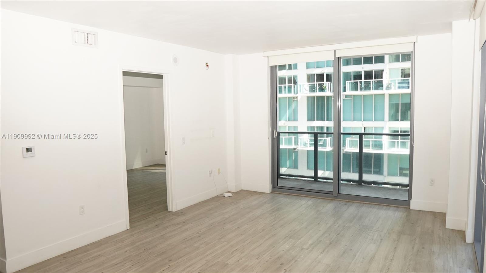 31 Southeast 6th Street, Unit 1108 Miami, FL 33131 - Photo 8 of 22 an empty room with wooden floor and windows