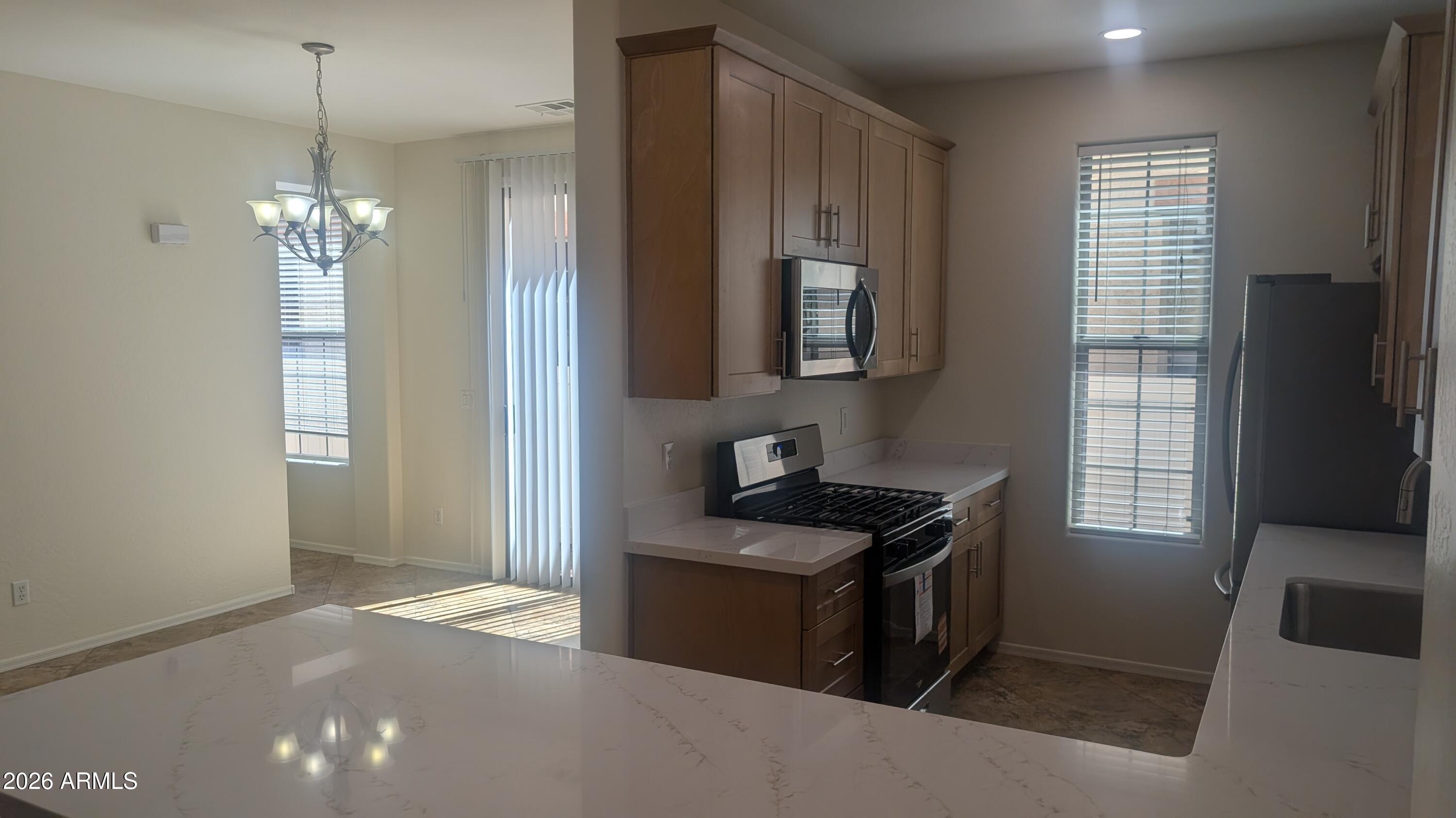 1453 South Sinova Avenue Gilbert, AZ 85296 - Photo 10 of 46 a kitchen that has a sink stainless steel appliances a window and a counter top space