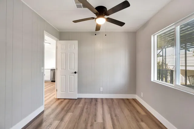 a view of an empty room with a window and wooden floor