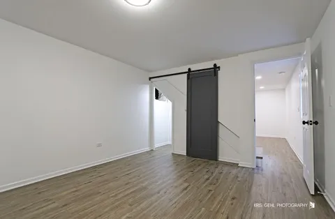 a view of an empty room with wooden floor and a bathroom