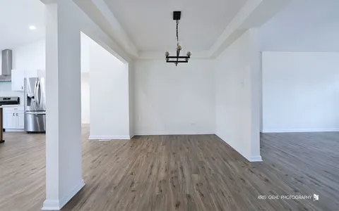 a view of a hallway with wooden floor and a ceiling fan