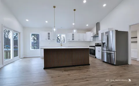 a kitchen with kitchen island white cabinets stainless steel appliances and wooden floor