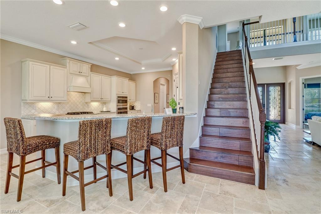 9902 Corso Bello Drive Naples, FL 34113 - Photo 28 of 45 a kitchen with granite countertop lots of wooden furniture and stainless steel appliances