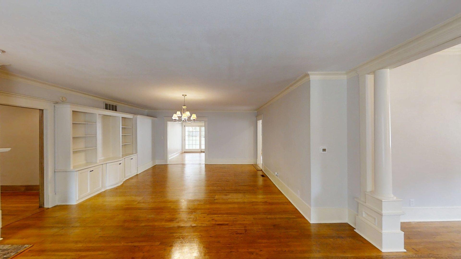 219 F Street Southwest Ardmore, OK 73401 - Photo 3 of 58 Hardwood flooring, built-in shelving, chandelier lighting, crown molding, and decorative columns