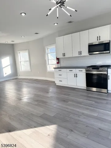 a kitchen with stainless steel appliances kitchen island granite countertop a stove a sink and white cabinets