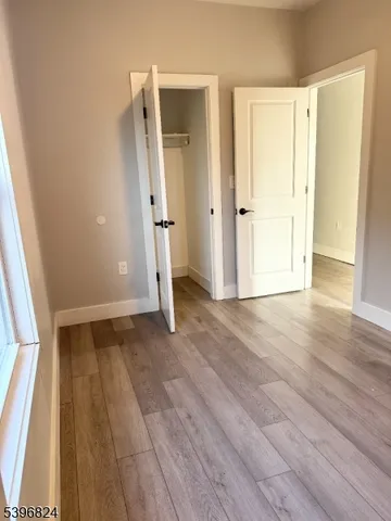 an empty room with wooden floor and a bathroom