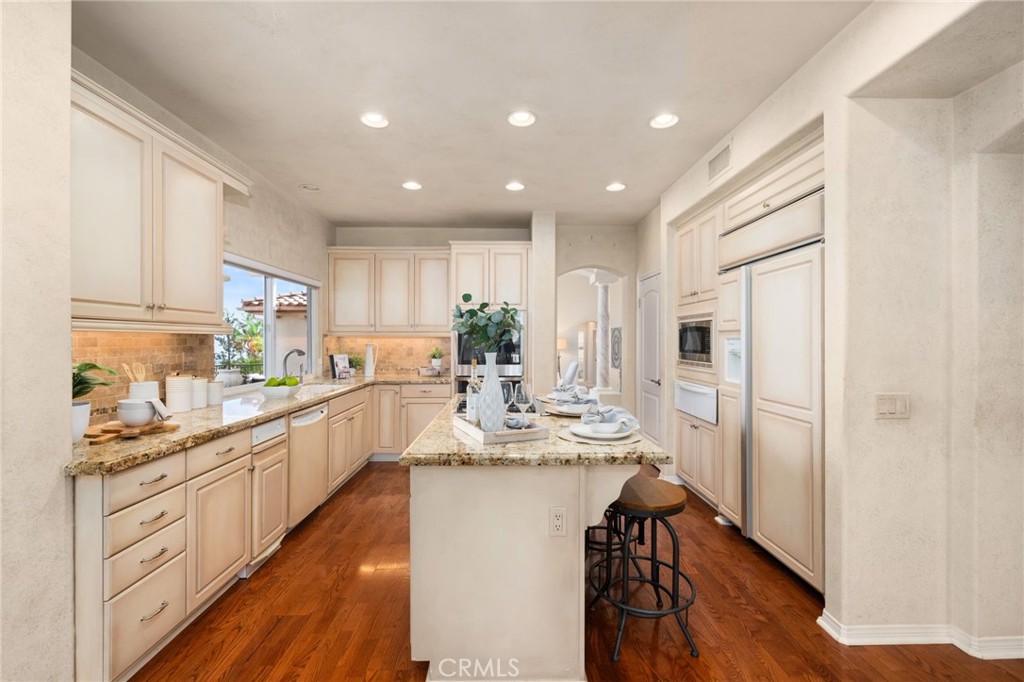 5501 Carriage Place Rancho Cucamonga, CA 91737 - Photo 15 of 60 a kitchen with kitchen island granite countertop a refrigerator a sink dishwasher a stove and white cabinets with wooden floor