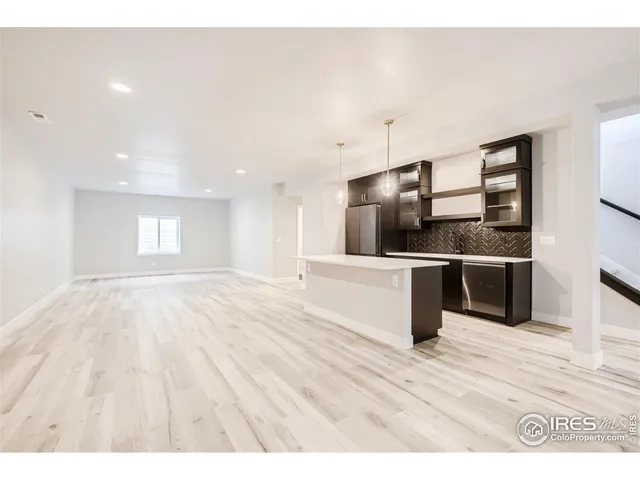 a kitchen with stainless steel appliances granite countertop a refrigerator a stove and a sink with wooden floor