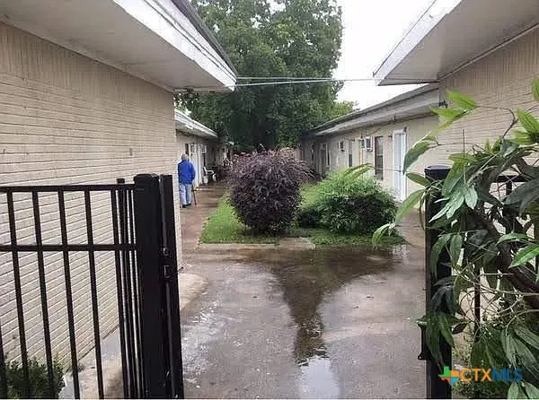 a view of a house with a small yard and floor to ceiling window and potted plants