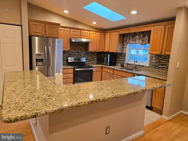 a kitchen with stainless steel appliances granite countertop sink refrigerator and microwave
