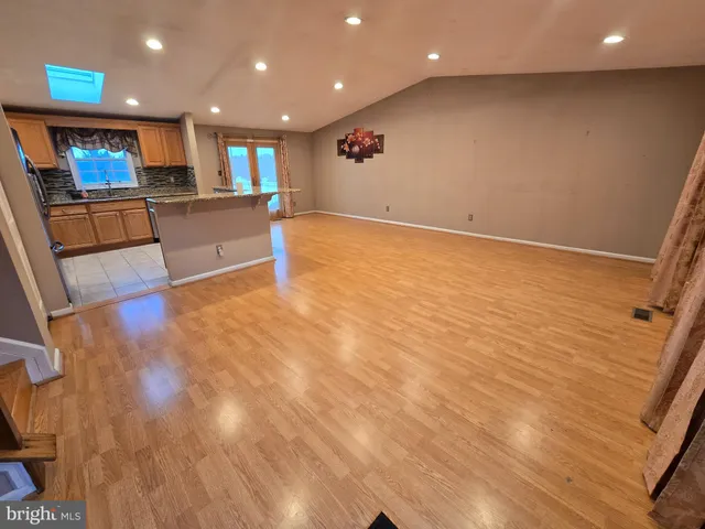 a view of kitchen with kitchen island wooden floor center island and stainless steel appliances