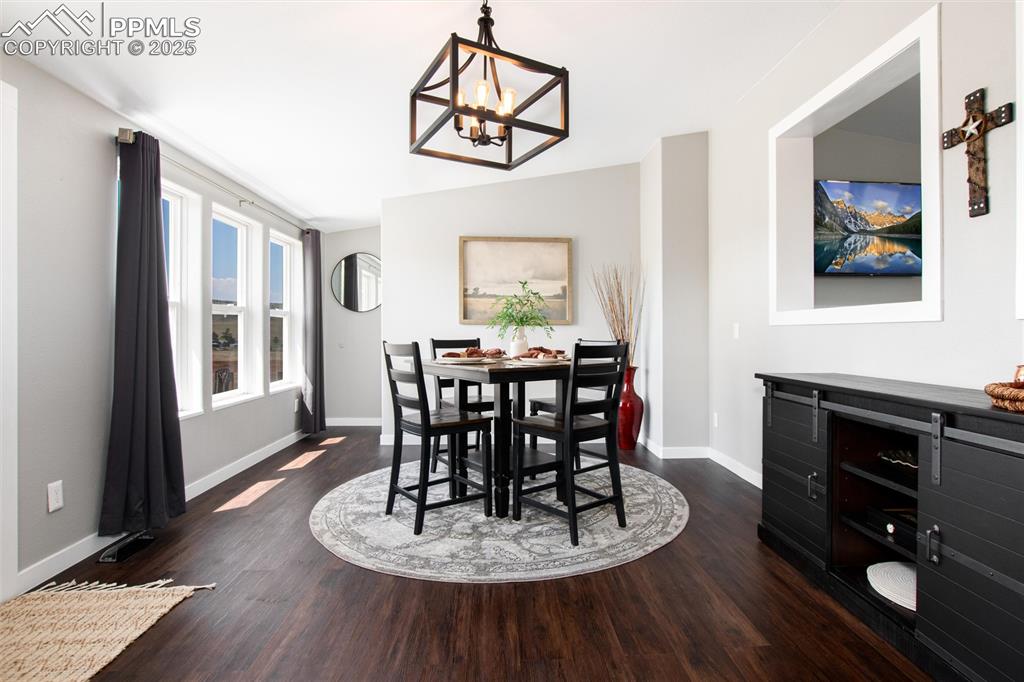 11100 Haskel Creek Road Larkspur, CO 80118 - Photo 13 of 49 a dining room with wooden floor a chandelier a wooden table and chairs