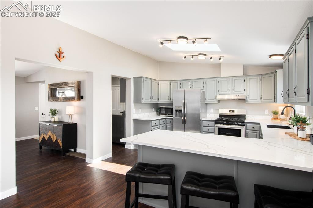 11100 Haskel Creek Road Larkspur, CO 80118 - Photo 17 of 49 a kitchen with refrigerator a stove a sink dishwasher and white cabinets with wooden floor
