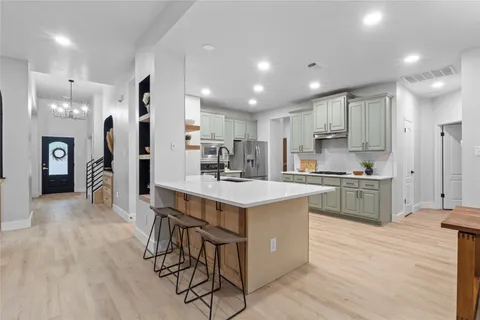a large kitchen with kitchen island a sink a stove a dining table and chairs