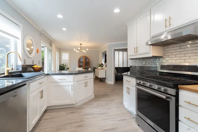 a kitchen with stainless steel appliances granite countertop a stove a sink and a refrigerator