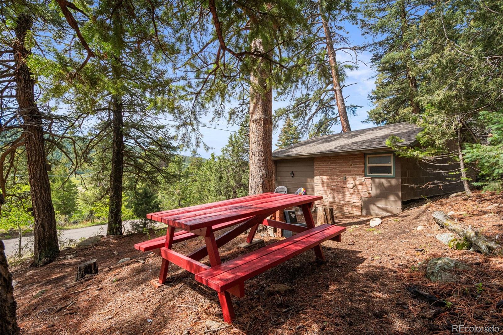 25845 Wilkerson Road Conifer, CO 80433 - Photo 2 of 16 a view of a wooden chairs and fire pit in the backyard