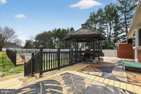 a view of a patio with table and chairs under an umbrella with a barbeque grill and plants