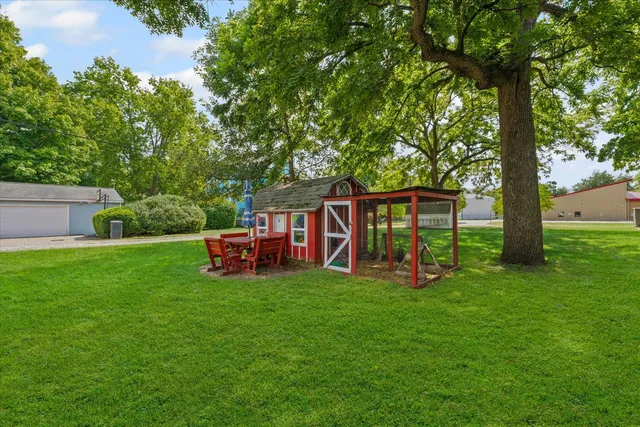 a backyard of a house with plants and large tree