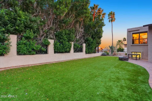 a view of a backyard with couches plants and large trees