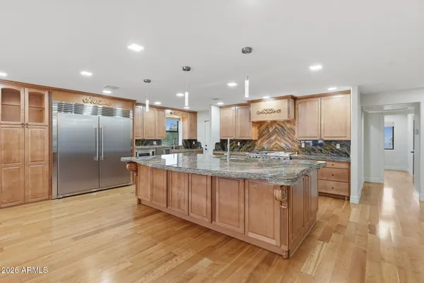 a large kitchen with stainless steel appliances kitchen island granite countertop a large counter top and wooden floors