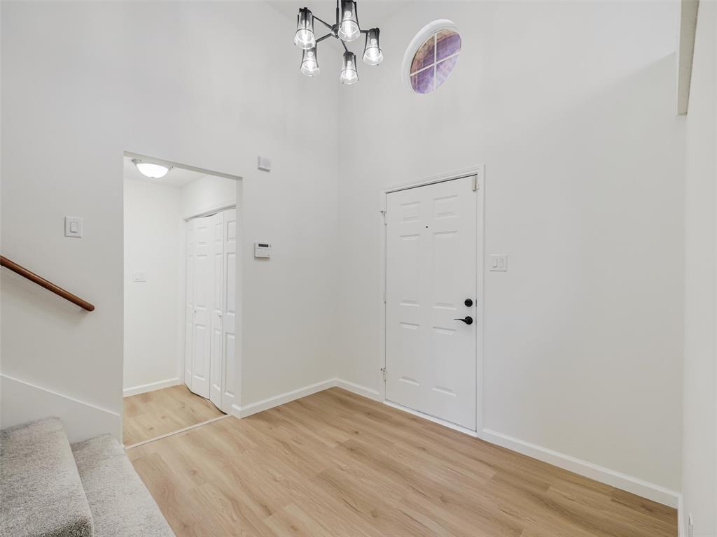 Entryway featuring wood-finish flooring, a contemporary chandelier, a round transom window, and a paneled entry door with black hardware