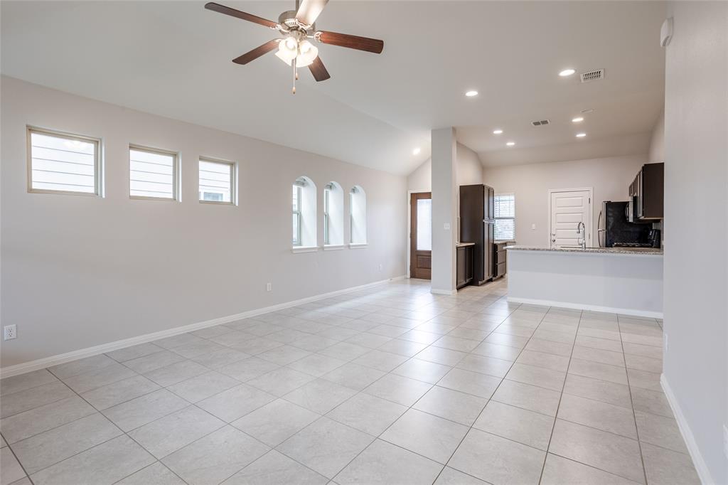 615 Stampede Road San Marcos, TX 78666 - Photo 22 of 26 An open-concept living space with lofty ceilings and integrated kitchen, featuring clean tile flooring throughout.