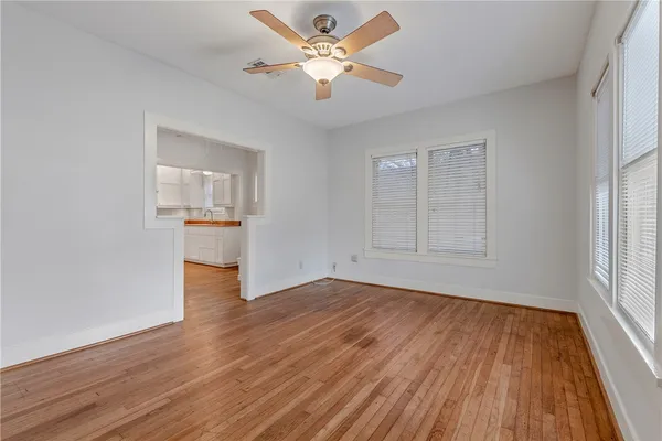 an empty room with wooden floor and a ceiling fan