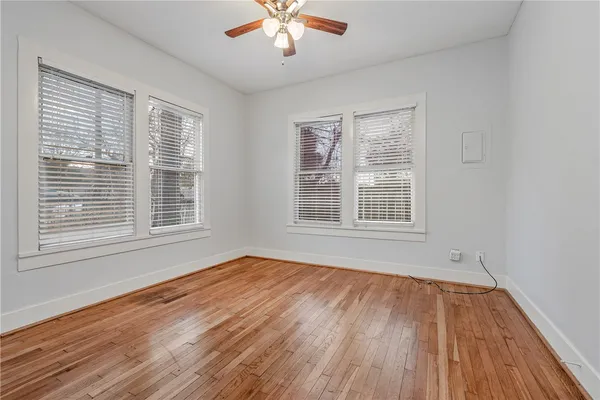 a view of an empty room with wooden floor and a window