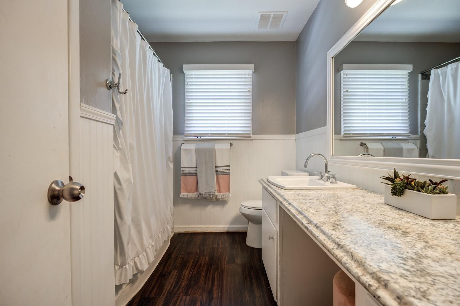 2306 61st Street Lubbock, TX 79412 - Photo 28 of 35 a bathroom with a granite countertop sink a toilet a window and a shower