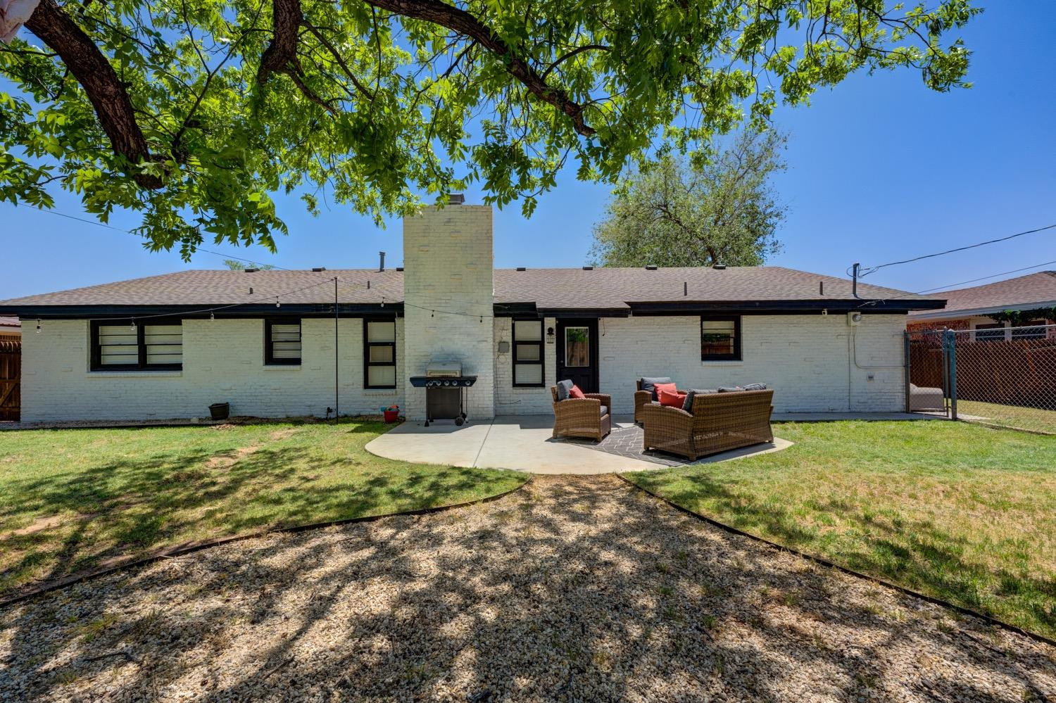 2306 61st Street Lubbock, TX 79412 - Photo 30 of 35 a view of a house with table and chairs under an umbrella
