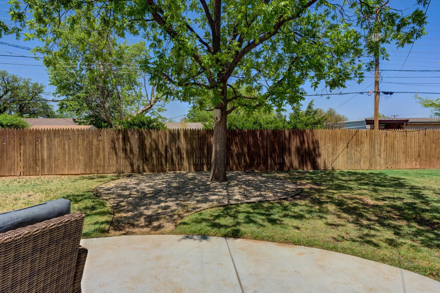 2306 61st Street Lubbock, TX 79412 - Photo 33 of 35 a view of a backyard with large trees and wooden fence